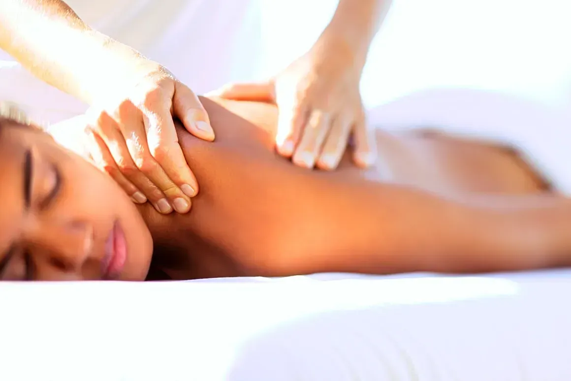 A woman is laying on a bed getting a massage.