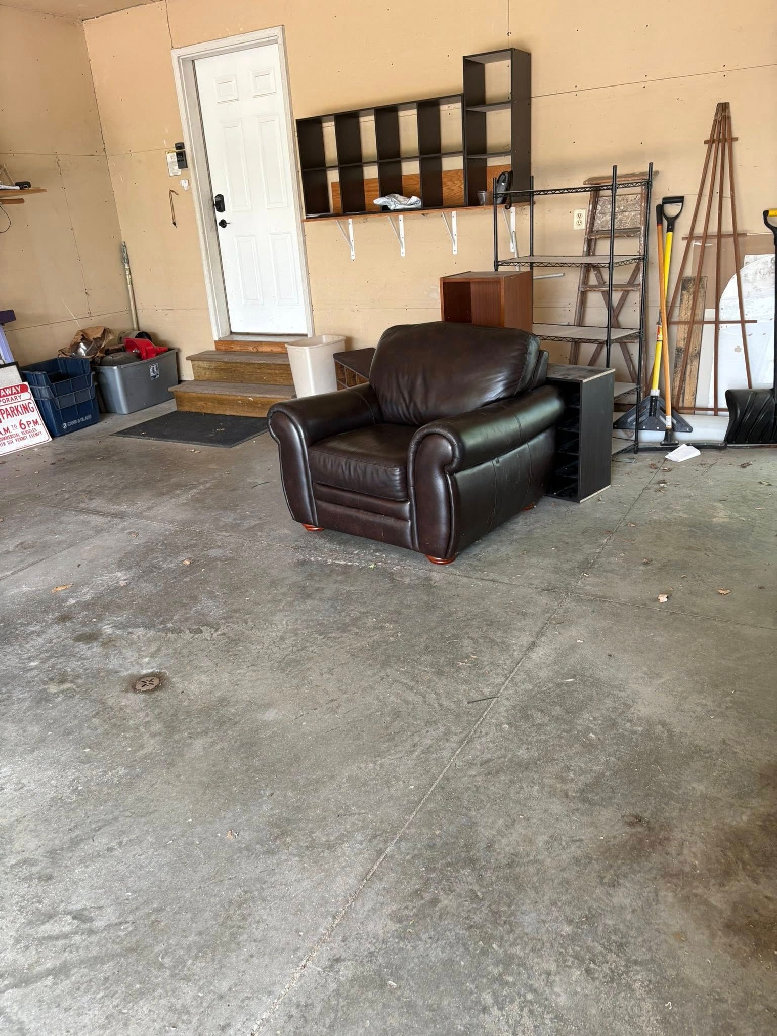 A brown leather chair is sitting in a garage.