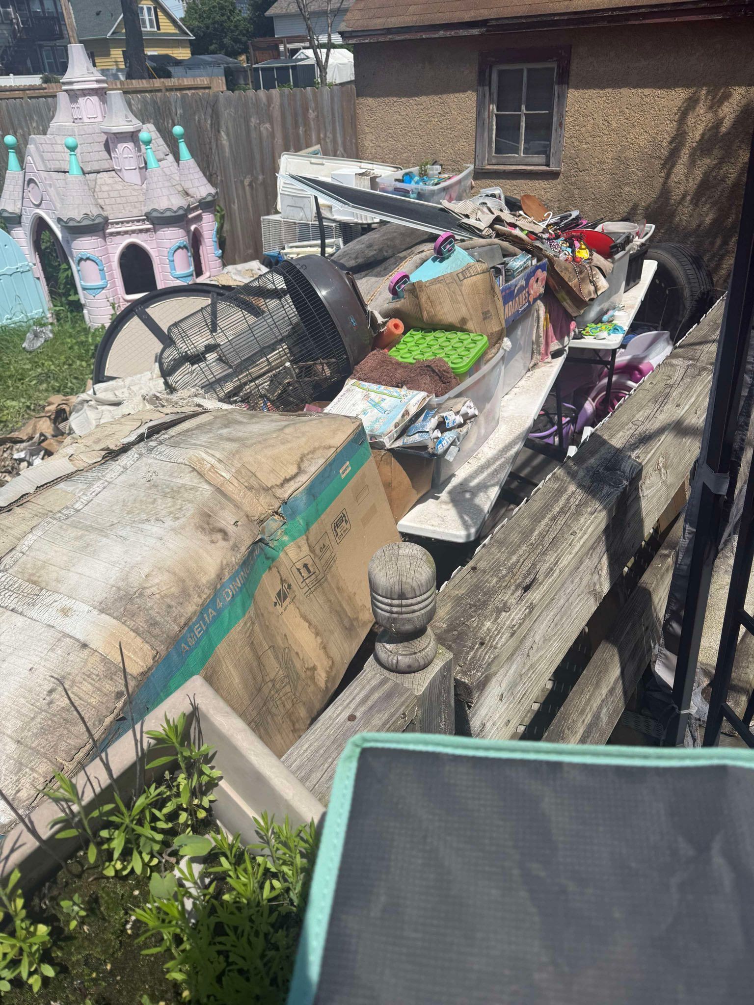 A pile of junk is sitting on top of a wooden fence in front of a house.