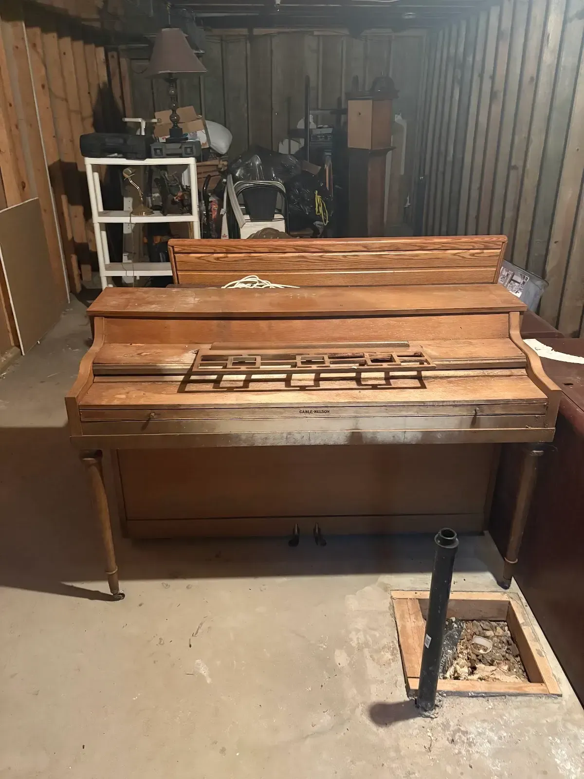 A wooden piano is sitting in a basement.