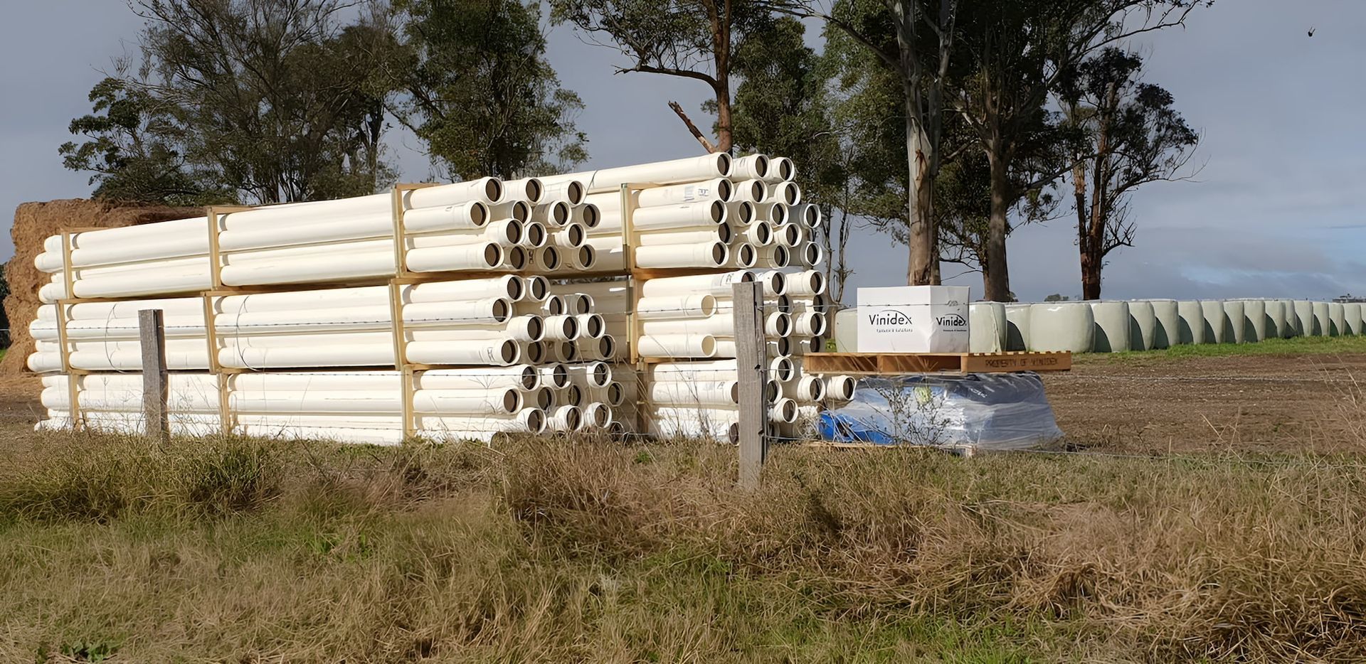 A Pile Of White Pipes Sit In A Field — Manning Valley Pumps And Irrigation In Gloucester, NSW