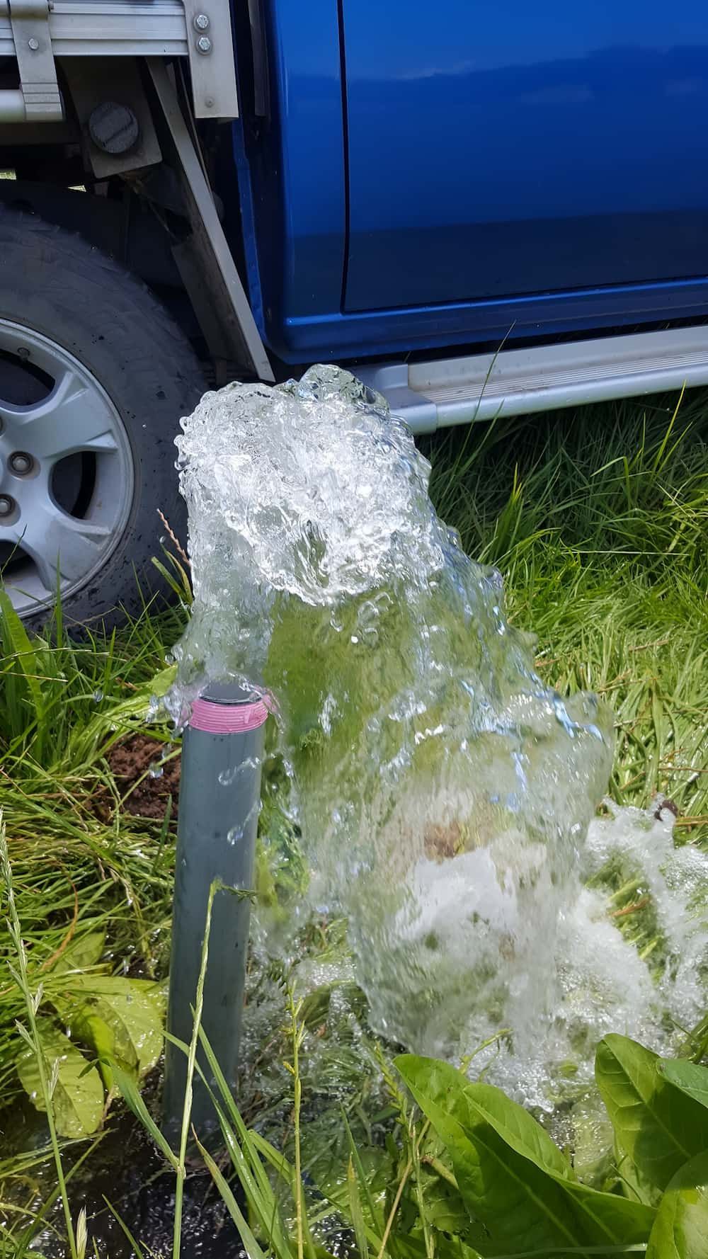 A Blue Truck Is Parked Next To A Pipe With Water — Manning Valley Pumps And Irrigation In Wingham, NSW