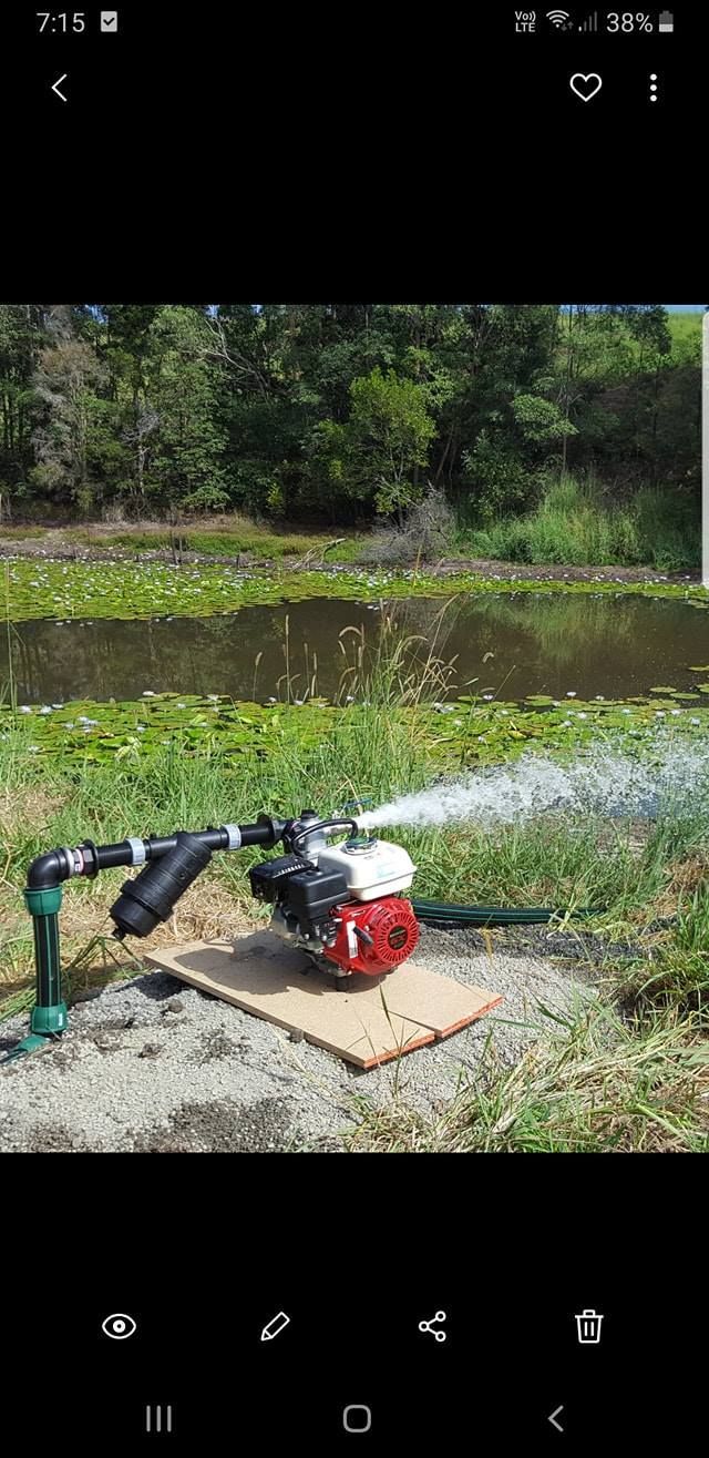 A water pump is sitting next to a body of water. — Manning Valley Pumps And Irrigation In Wingham, NSW