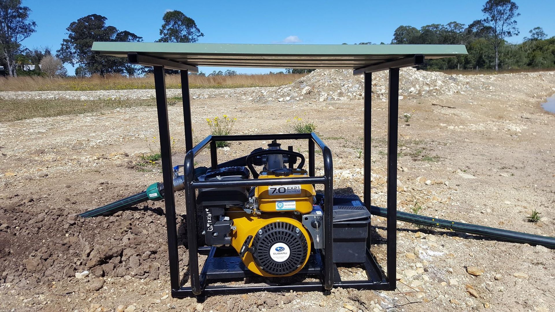 A yellow engine is sitting under a canopy in a field. — Manning Valley Pumps And Irrigation In Wingham, NSW