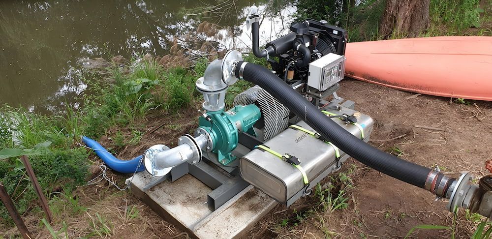 A Pump With A Hose Attached To It Is Sitting Next To A Water — Manning Valley Pumps And Irrigation In Taree, NSW