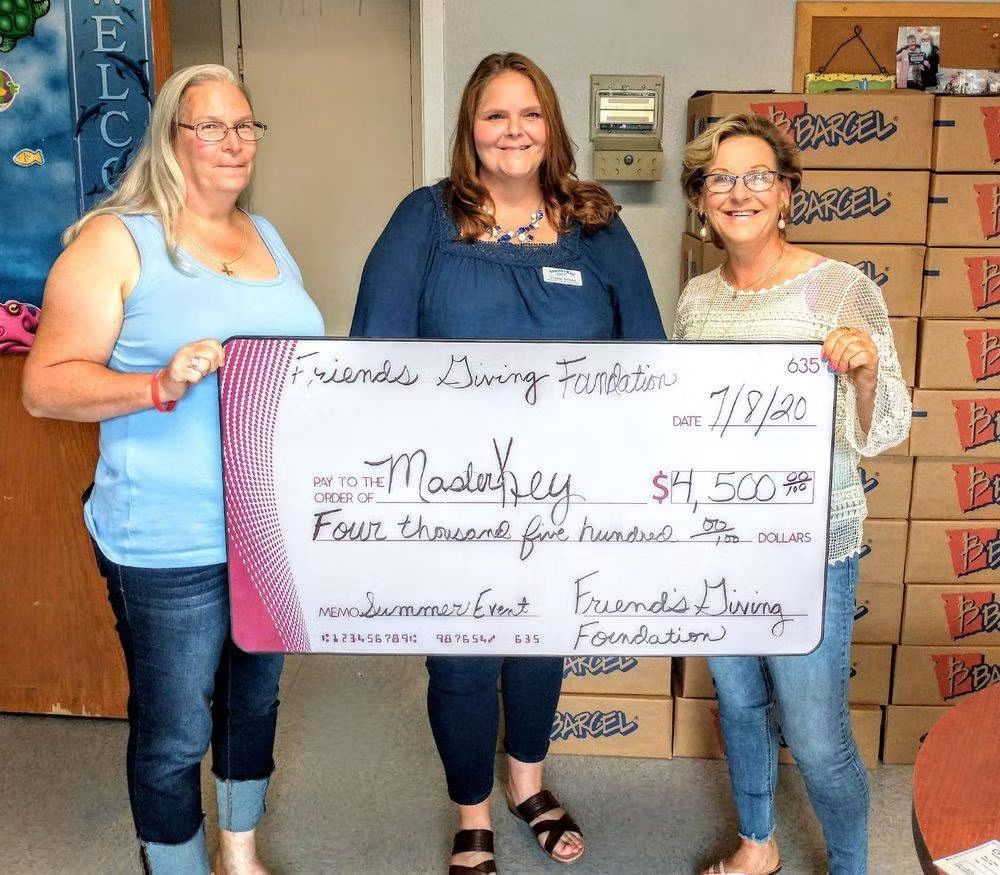 Three people holding a check for $4,500. The check is from Friends Dining Foundation, made out to Maday.