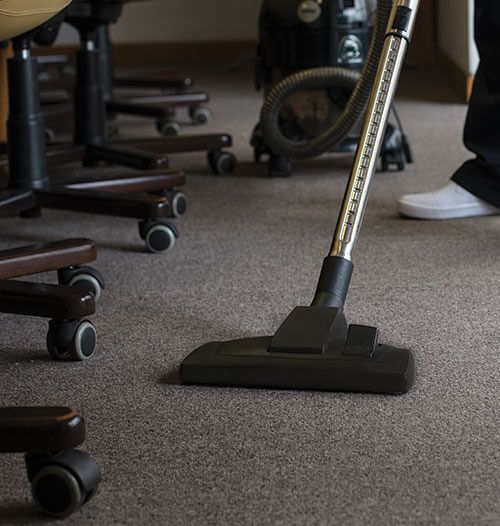 A person is using a vacuum cleaner on a carpeted floor.