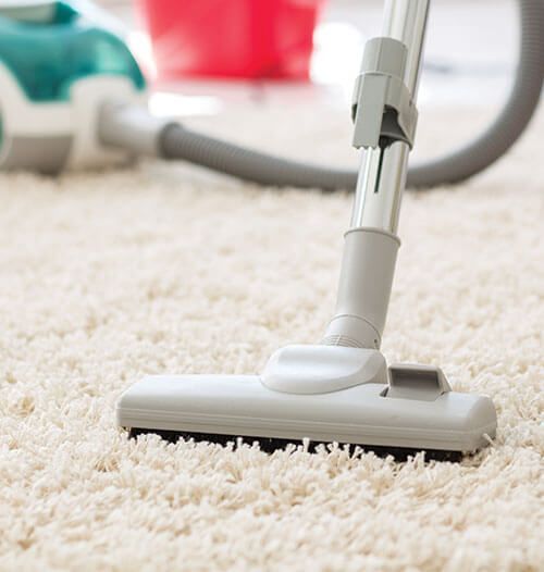 A vacuum cleaner is being used to clean a white carpet