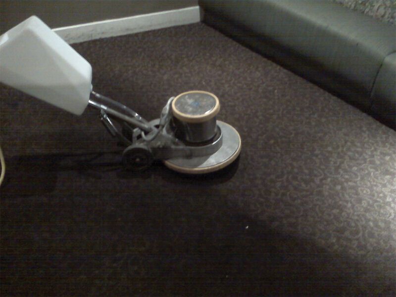 A machine is being used to clean a brown carpet