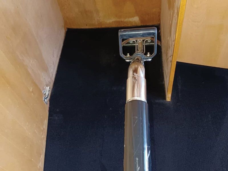 A vacuum cleaner is sitting on a black carpet in a room.