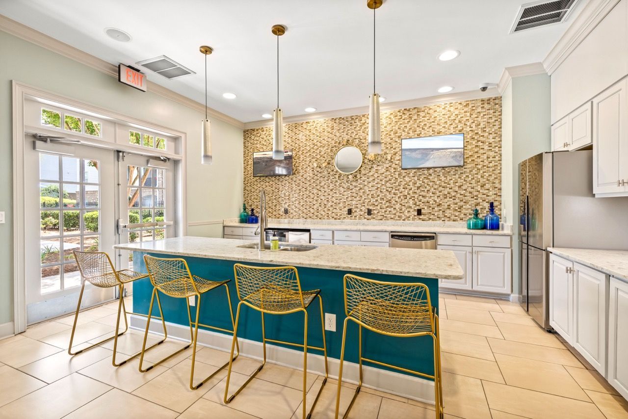 Bright community kitchen with a large island and gold bar stools.