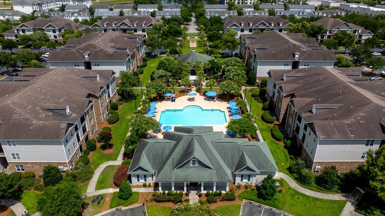 Aerial view of a residential apartment community with a central swimming pool and surrounding buildings.