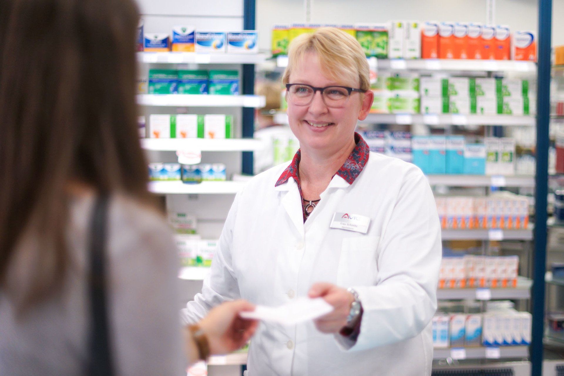 Eine Apothekerin gibt einer Frau in einer Apotheke ein Rezept.