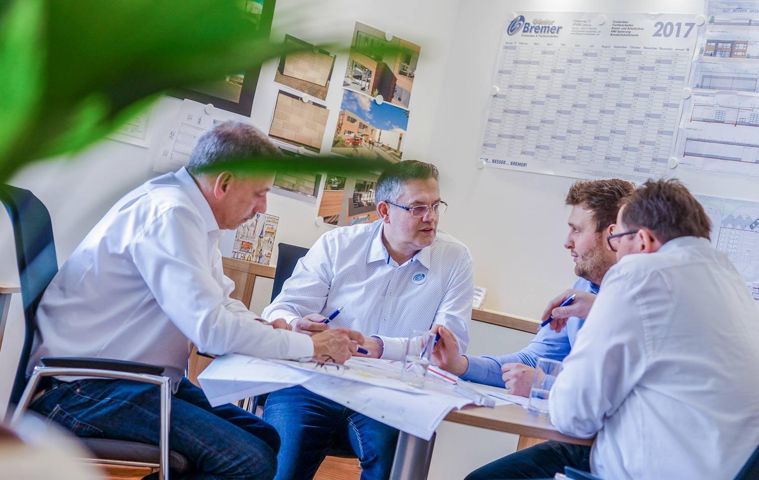 Eine Gruppe von Männern sitzt um einen Tisch herum und hält eine Besprechung ab.