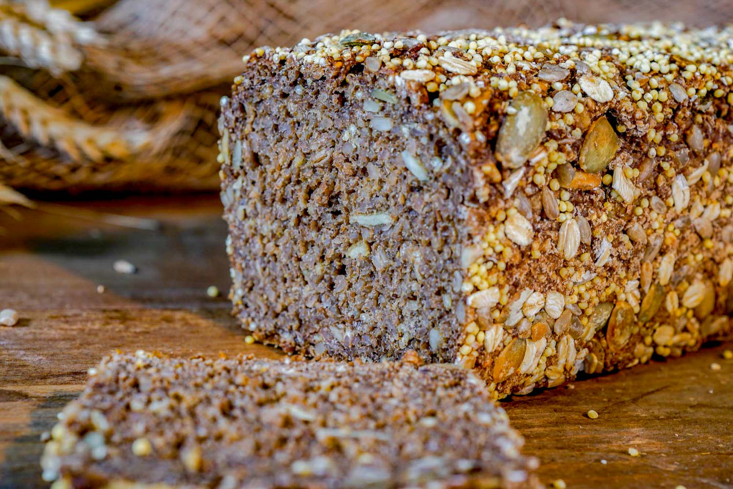 Auf einem Holztisch liegt ein Laib Brot mit Körnern.