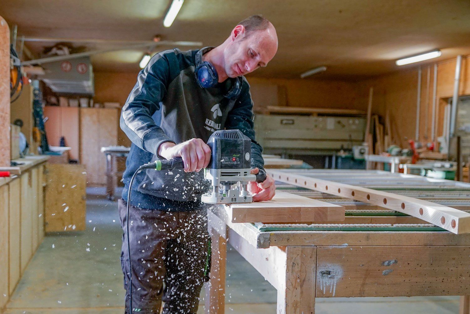 Ein Mann schneidet in einer Werkstatt mit einer Säge ein Stück Holz.