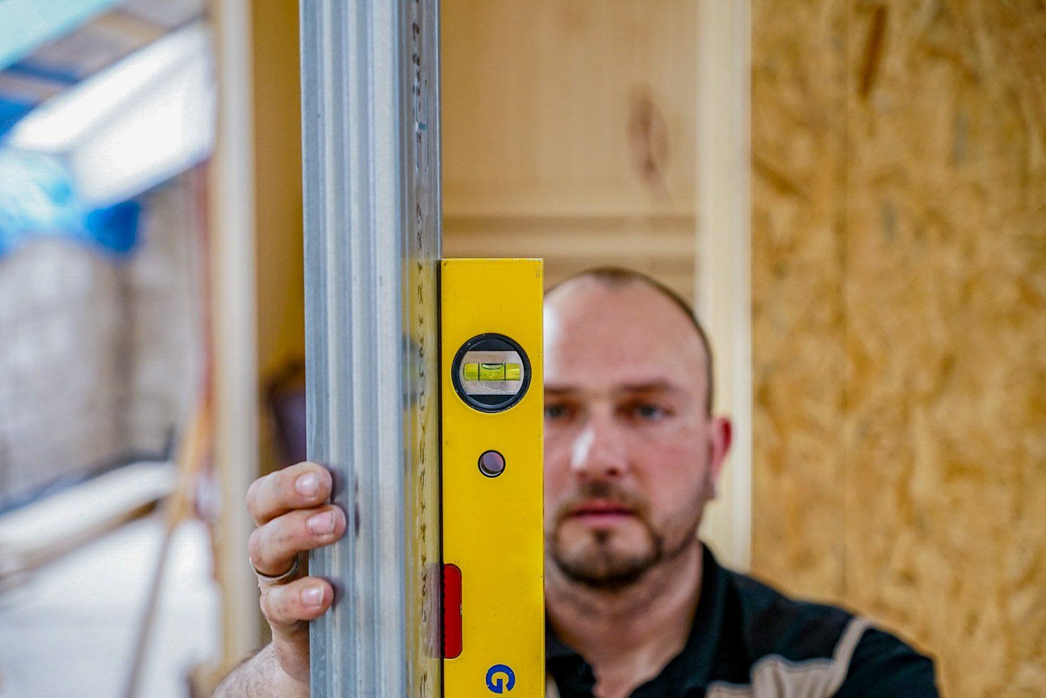 Ein Mann hält eine gelbe Wasserwaage in der Hand.