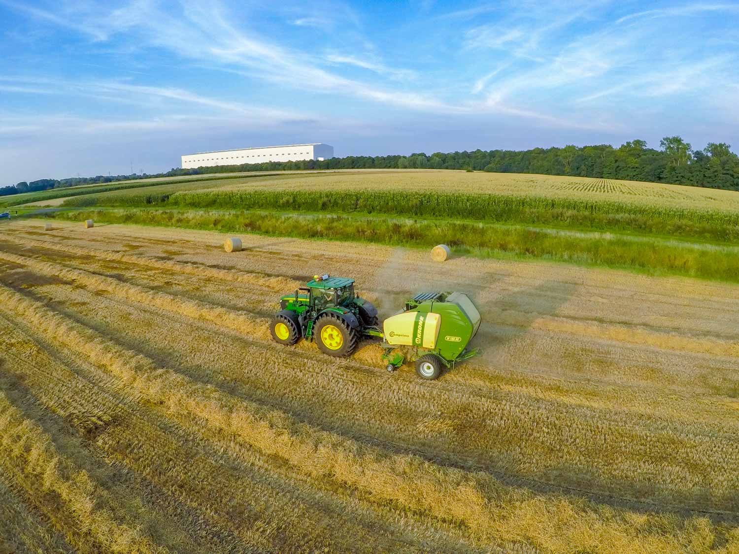 Eine Luftaufnahme eines Traktors, der auf einem Feld Heu presst.