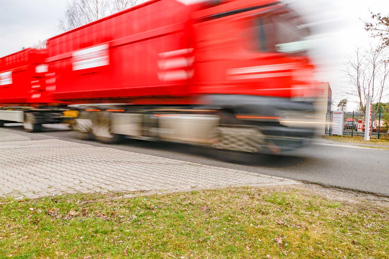 Auf einem verschwommenen Foto fährt ein roter Lastwagen eine Straße entlang.