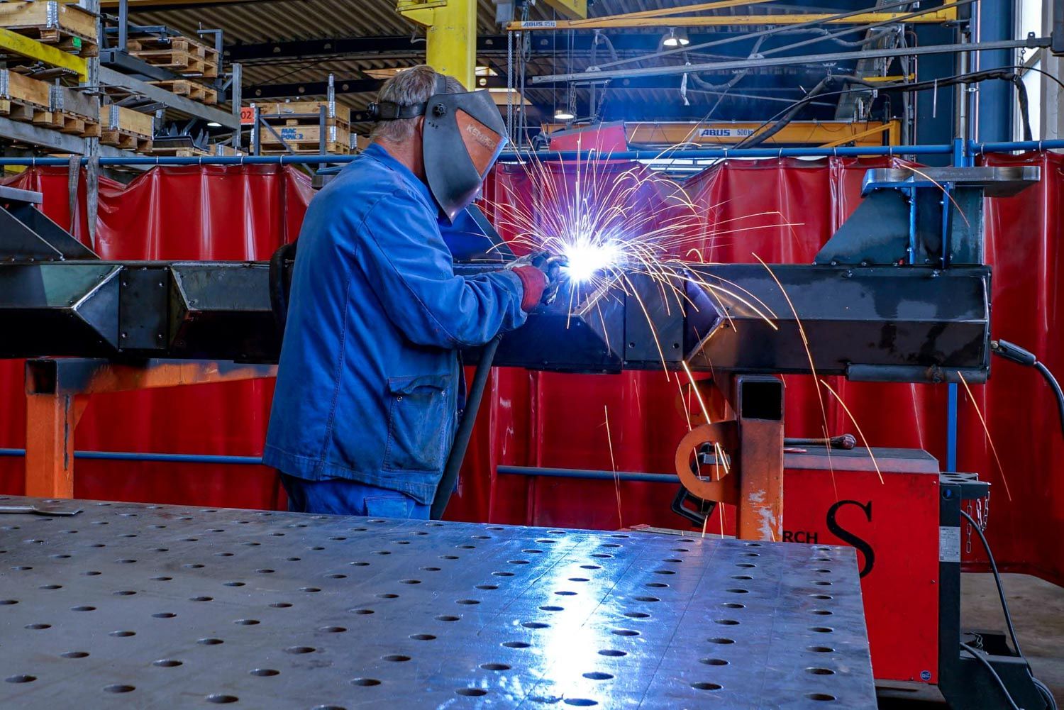 Ein Mann schweißt in einer Fabrik ein Stück Metall.