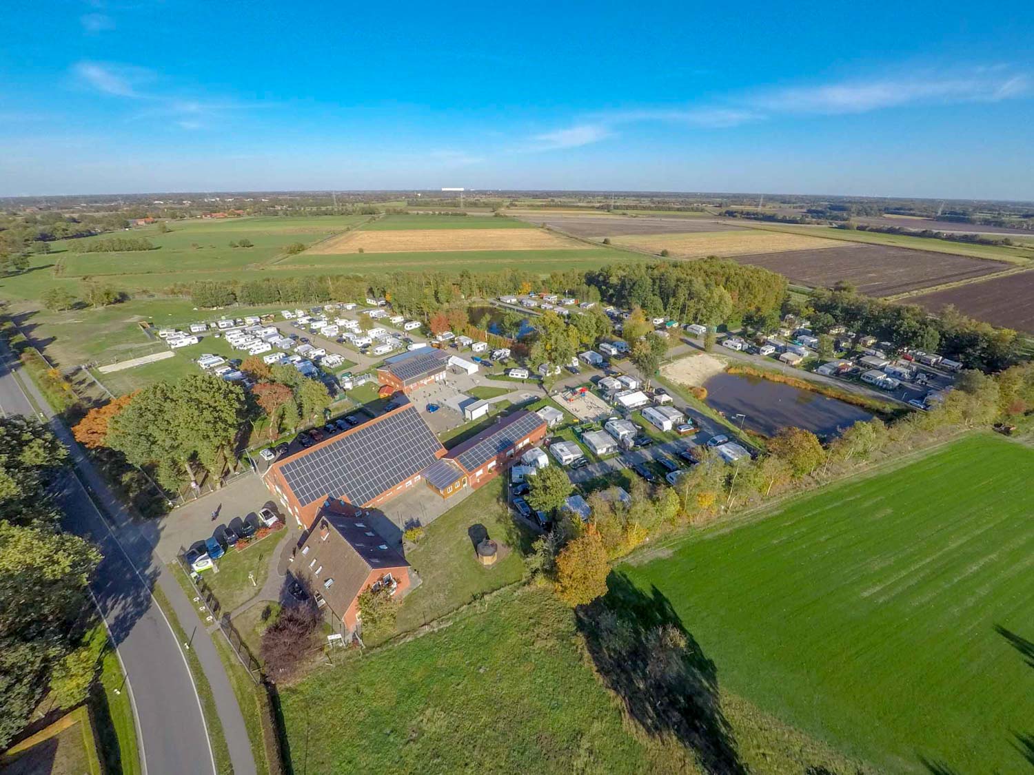 Eine Luftaufnahme eines Campingplatzes, umgeben von Feldern und Bäumen.