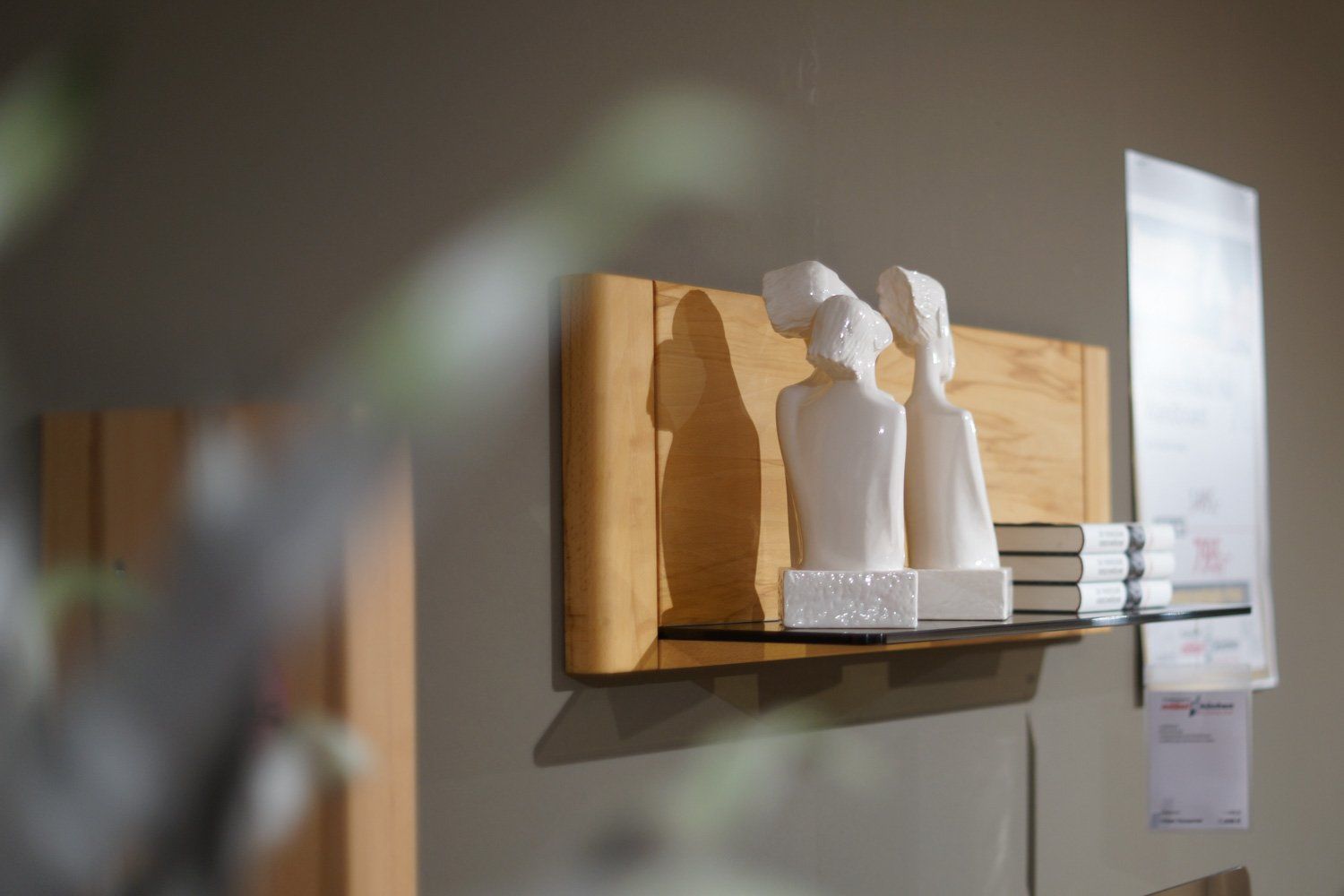 Ein Holzregal mit zwei weißen Statuen darauf.