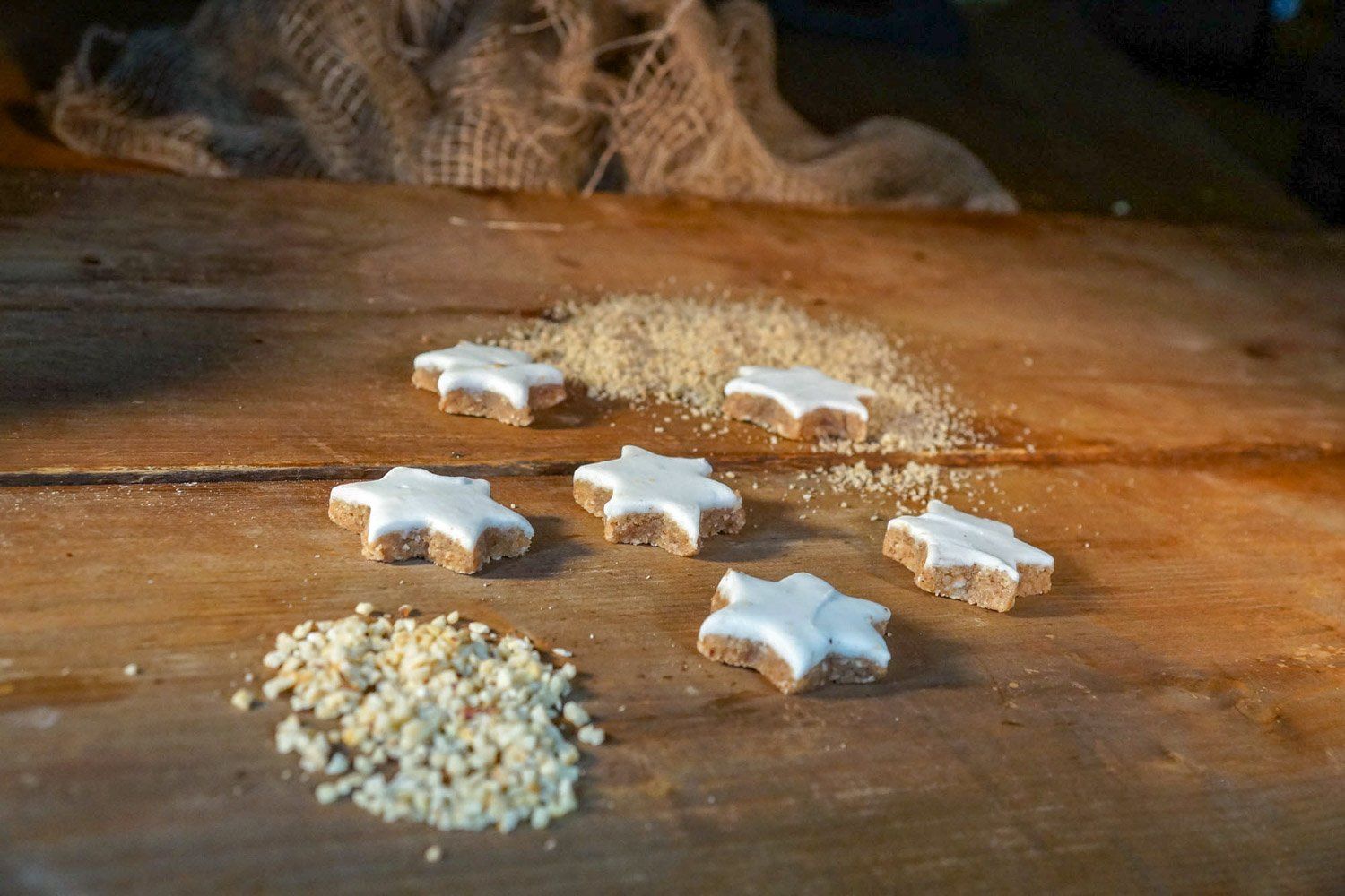 Ein Holztisch mit sternförmigen Keksen und Nüssen.