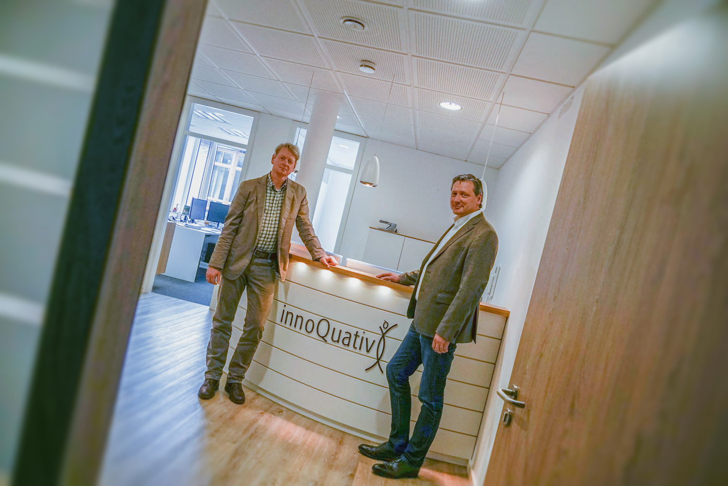 Zwei Männer stehen vor einem Empfangstresen in einem Büro.