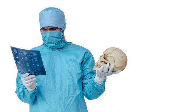 un dottore con una tuta protettiva, una mascherina e in mano una lastra e un teschio