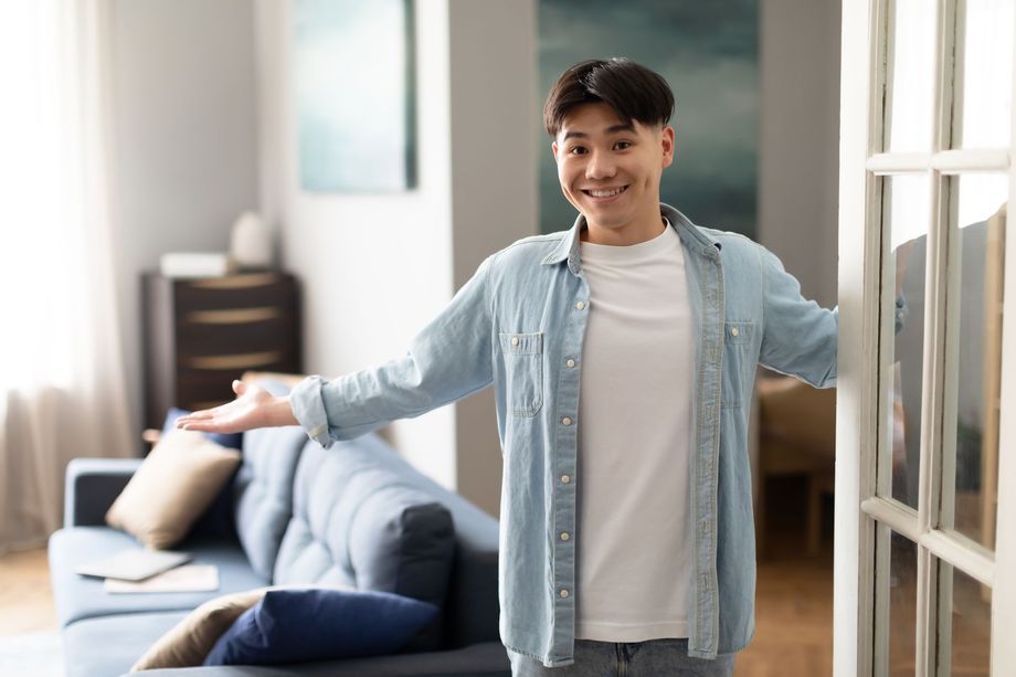 Smiling man welcomes guests into a living room.