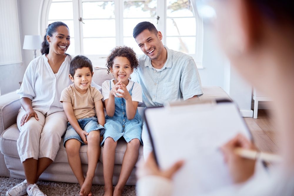 A family is sitting on a couch talking to a doctor.