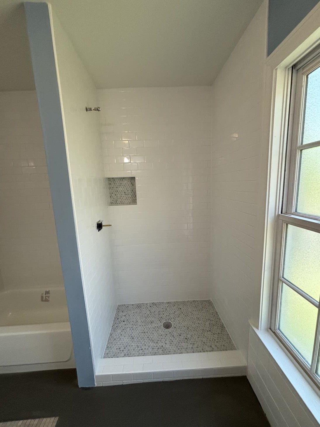 a man is installing tiles on a wall in a bathroom .