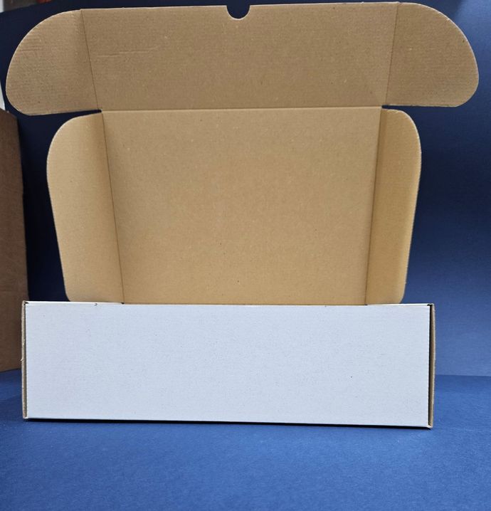 Scatola di cartone aperta, pannello frontale bianco, interno marrone, su superficie blu.