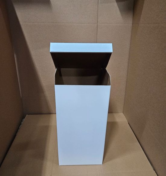 Scatola di cartone bianca aperta su sfondo marrone. Il coperchio è parzialmente aperto.