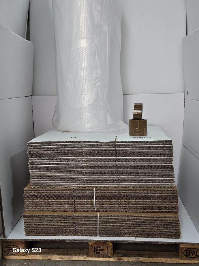 Pila di fogli di cartone con materiali di imballaggio su un pallet di legno.