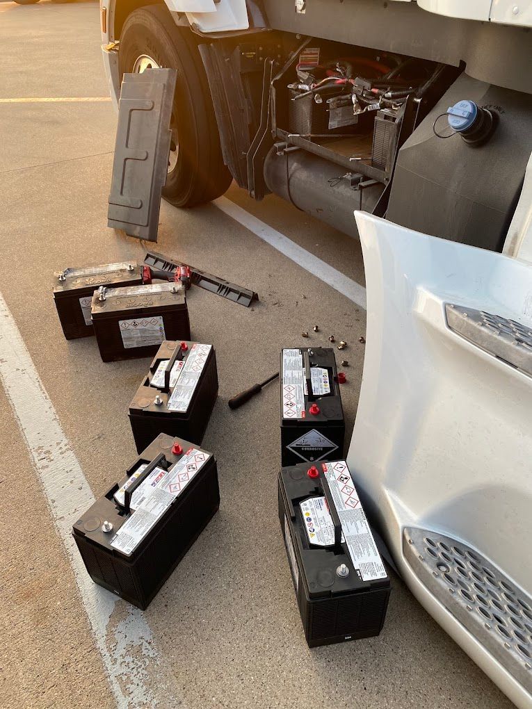 A bunch of batteries are sitting on the ground next to a truck.