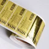 A roll of gold foil labels on a white surface.