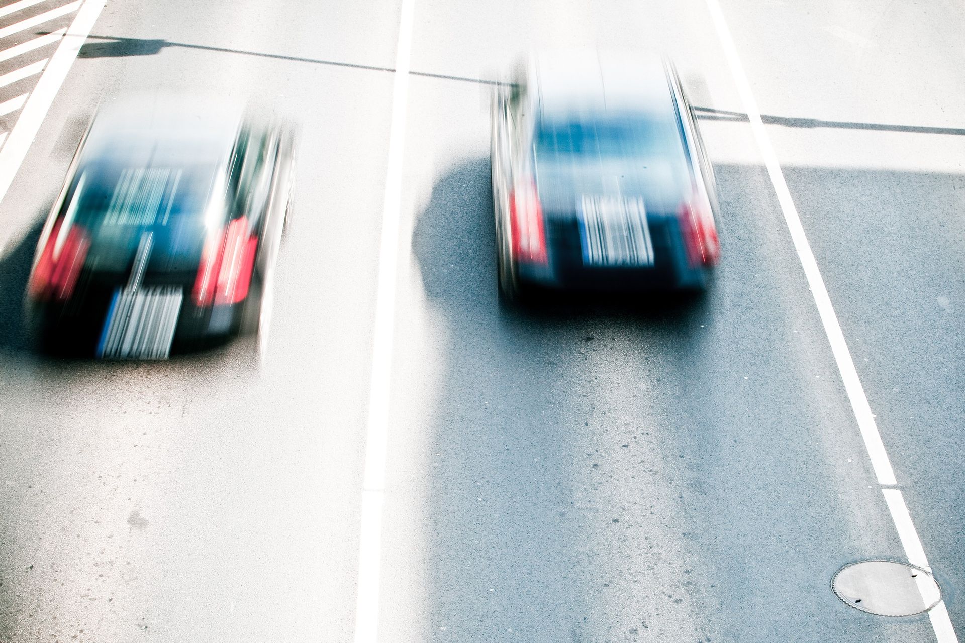 Two blurred black cars speeding down a road, creating motion streaks.