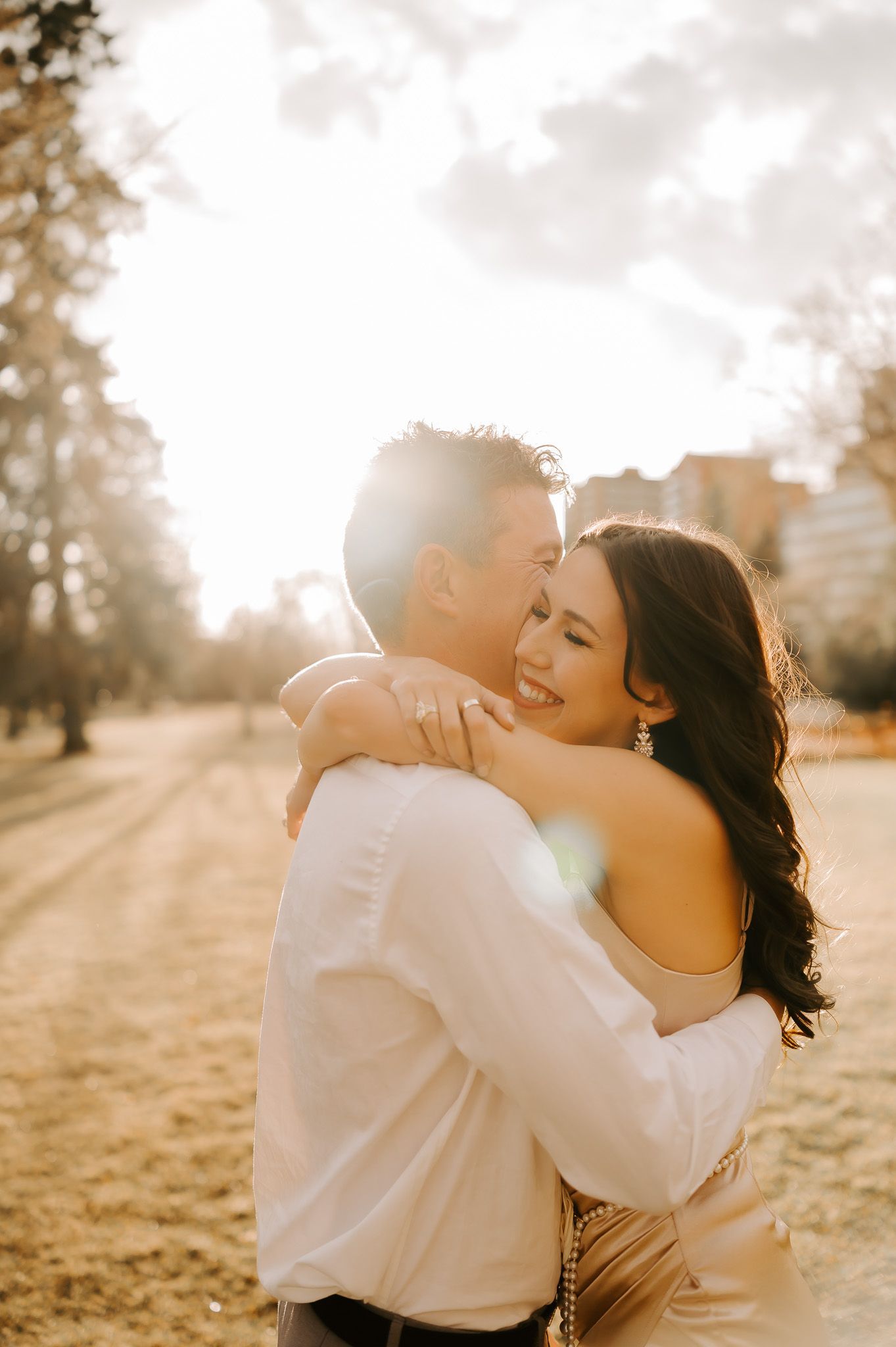 A man and a woman are hugging each other in a park.