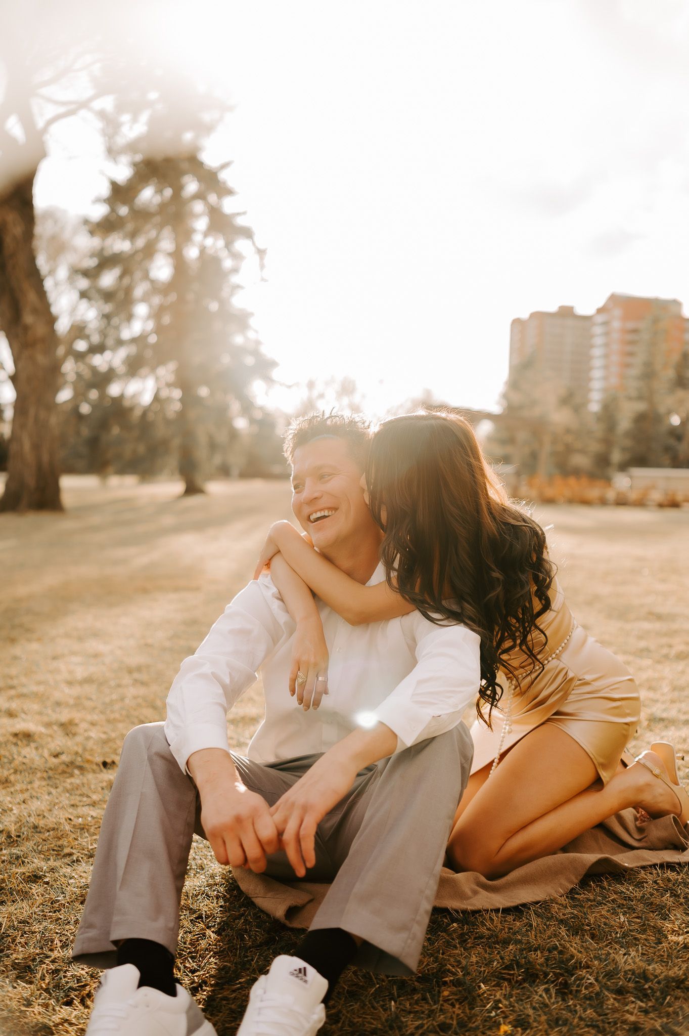 A man and a woman are sitting on a blanket in a park.