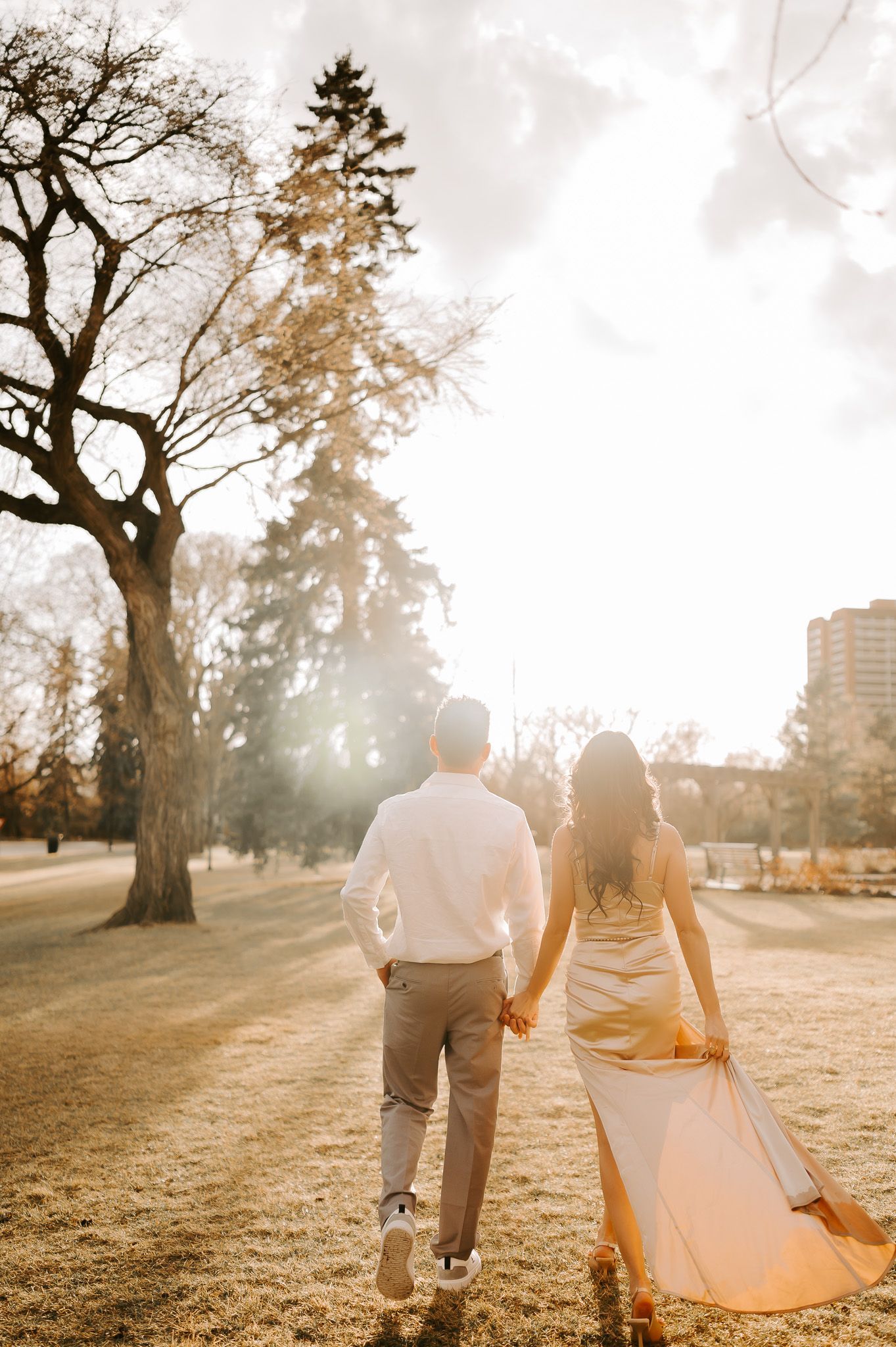 A man and a woman are walking in a park holding hands.