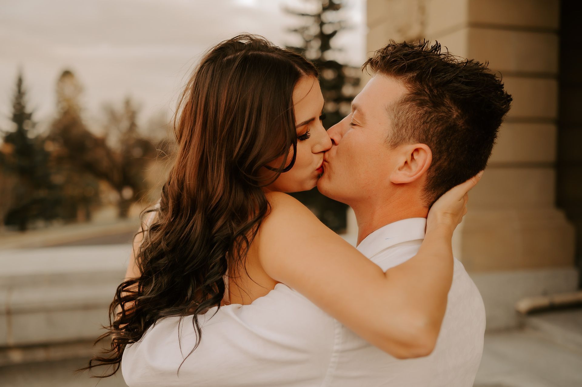 A man and a woman are kissing in front of a building.