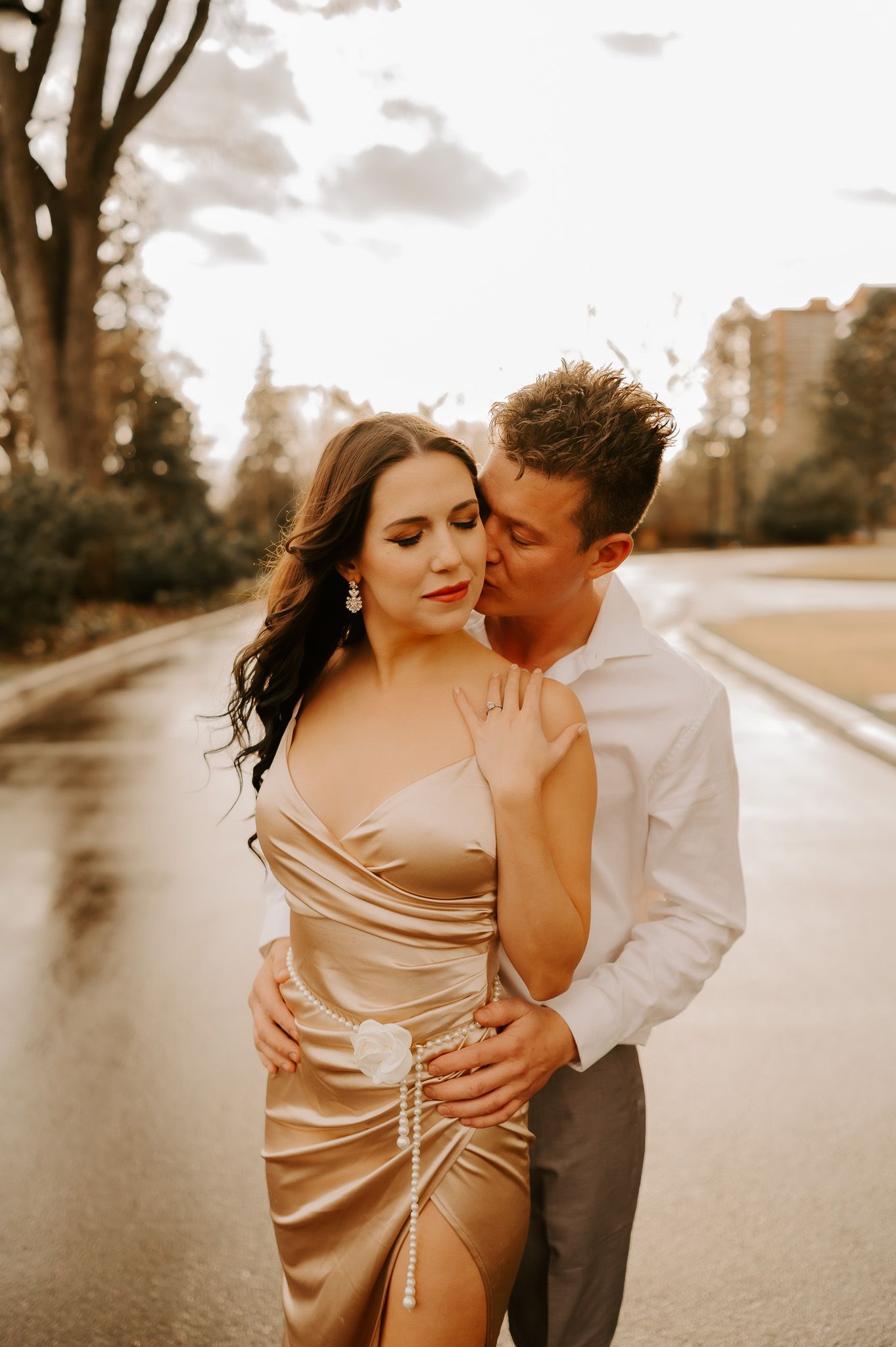 A man is kissing a woman on the cheek while they are walking down the street.