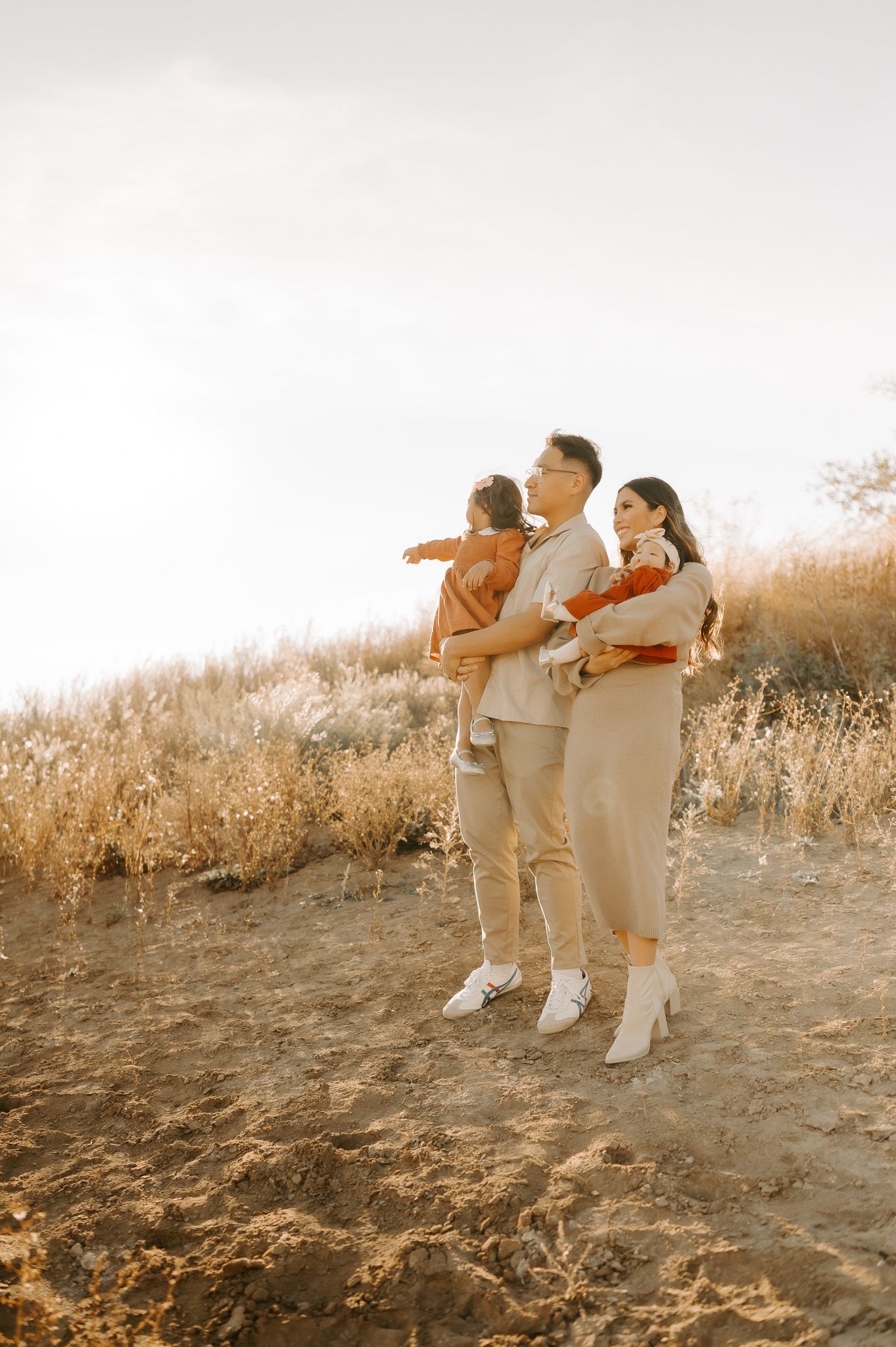 A family posing for photos in a field at sunset for family photography.