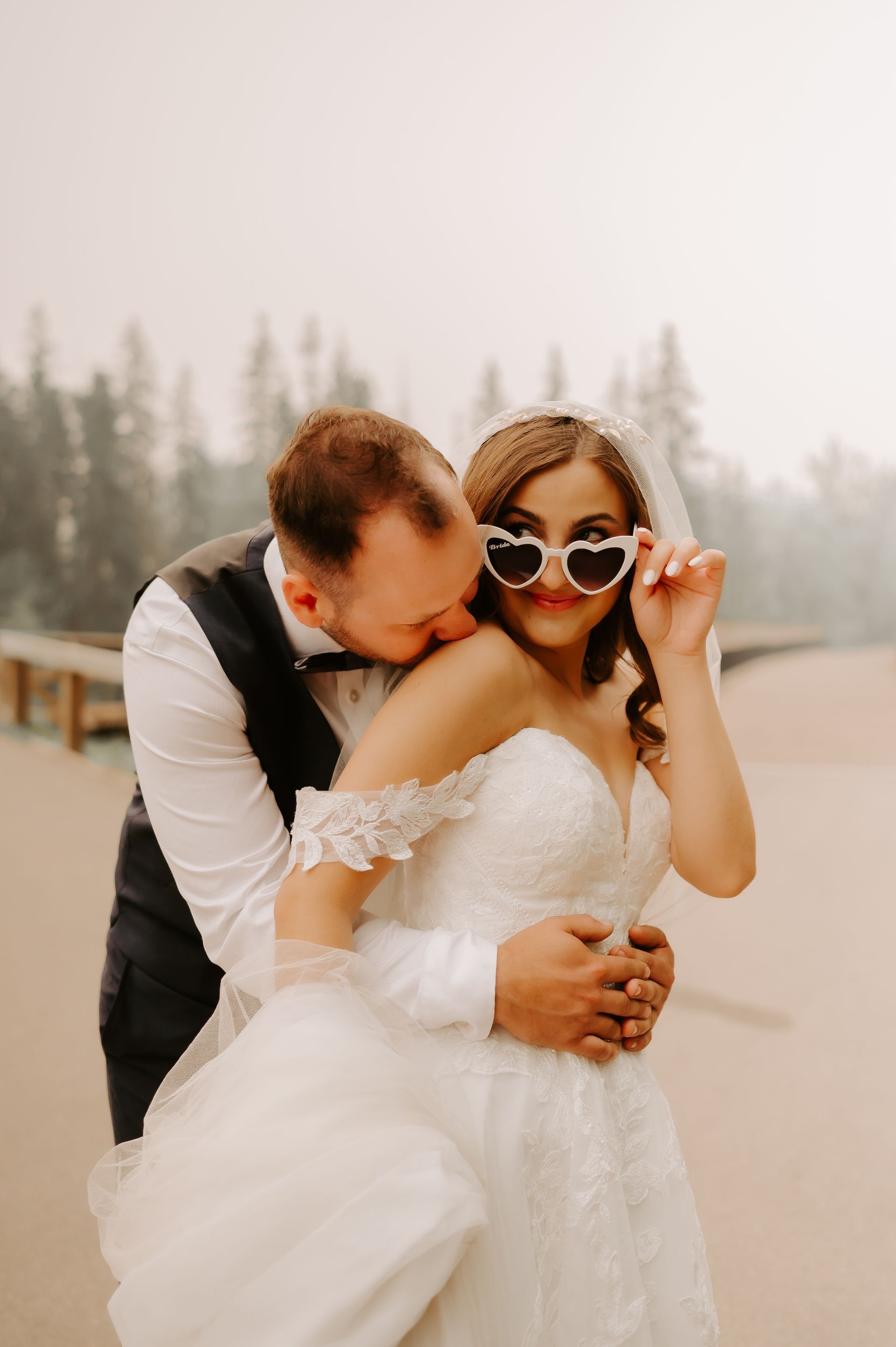 Wedding photography of a couple kissing with the sun shining through behind them.