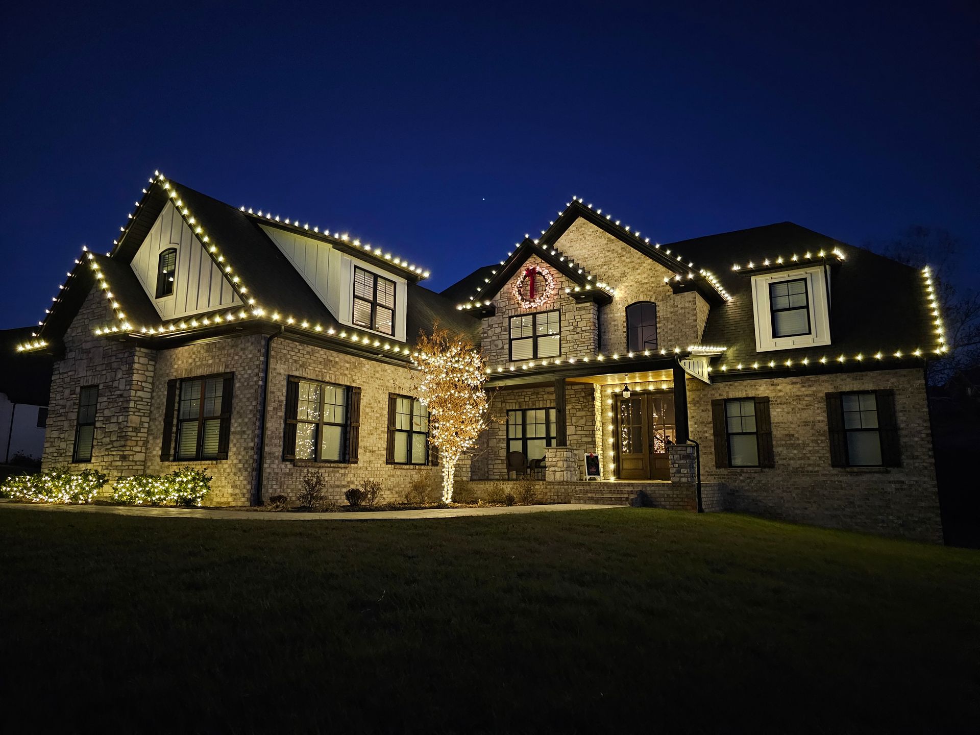 House at night illuminated with red lights, including rooflines and ground-level landscaping.
