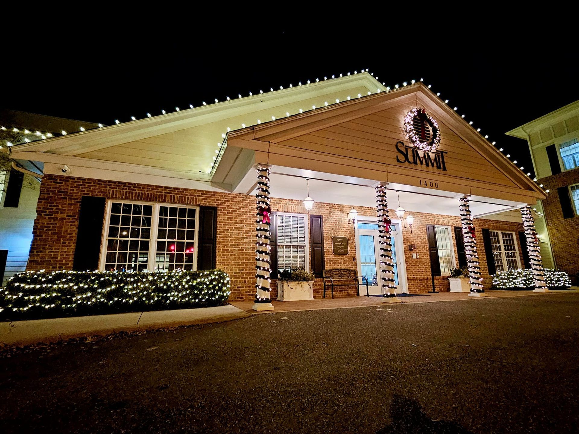 Building exterior at night, lit with Christmas lights; 