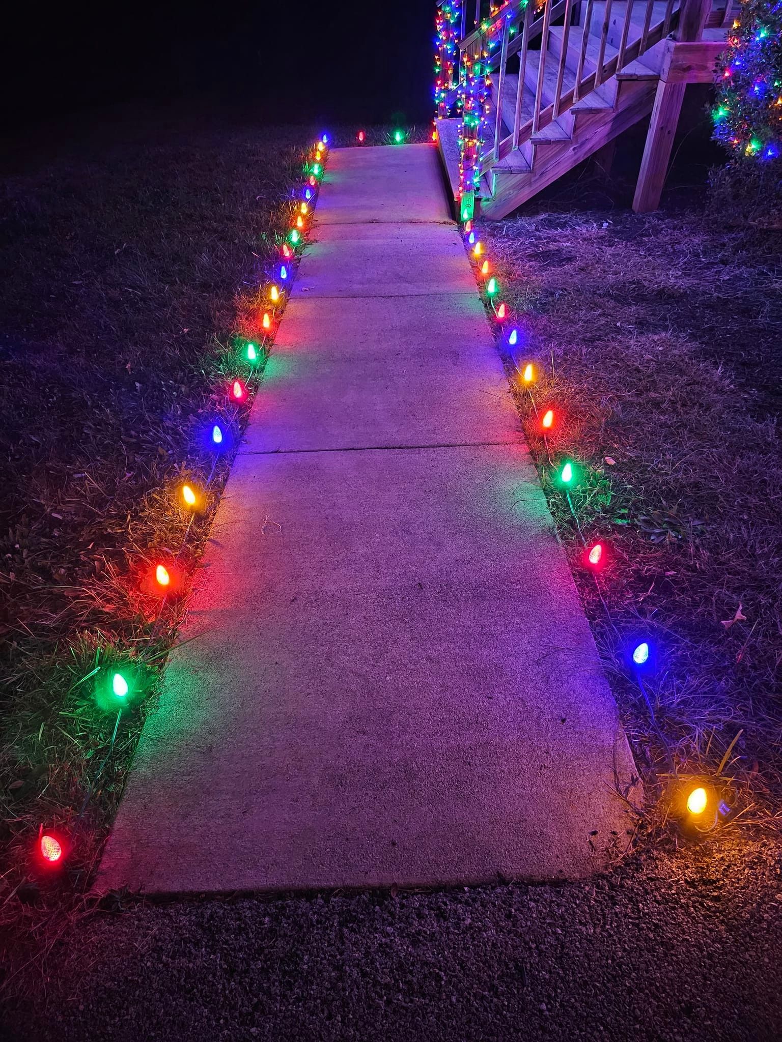 Pathway with colorful lights leading to a porch at night.