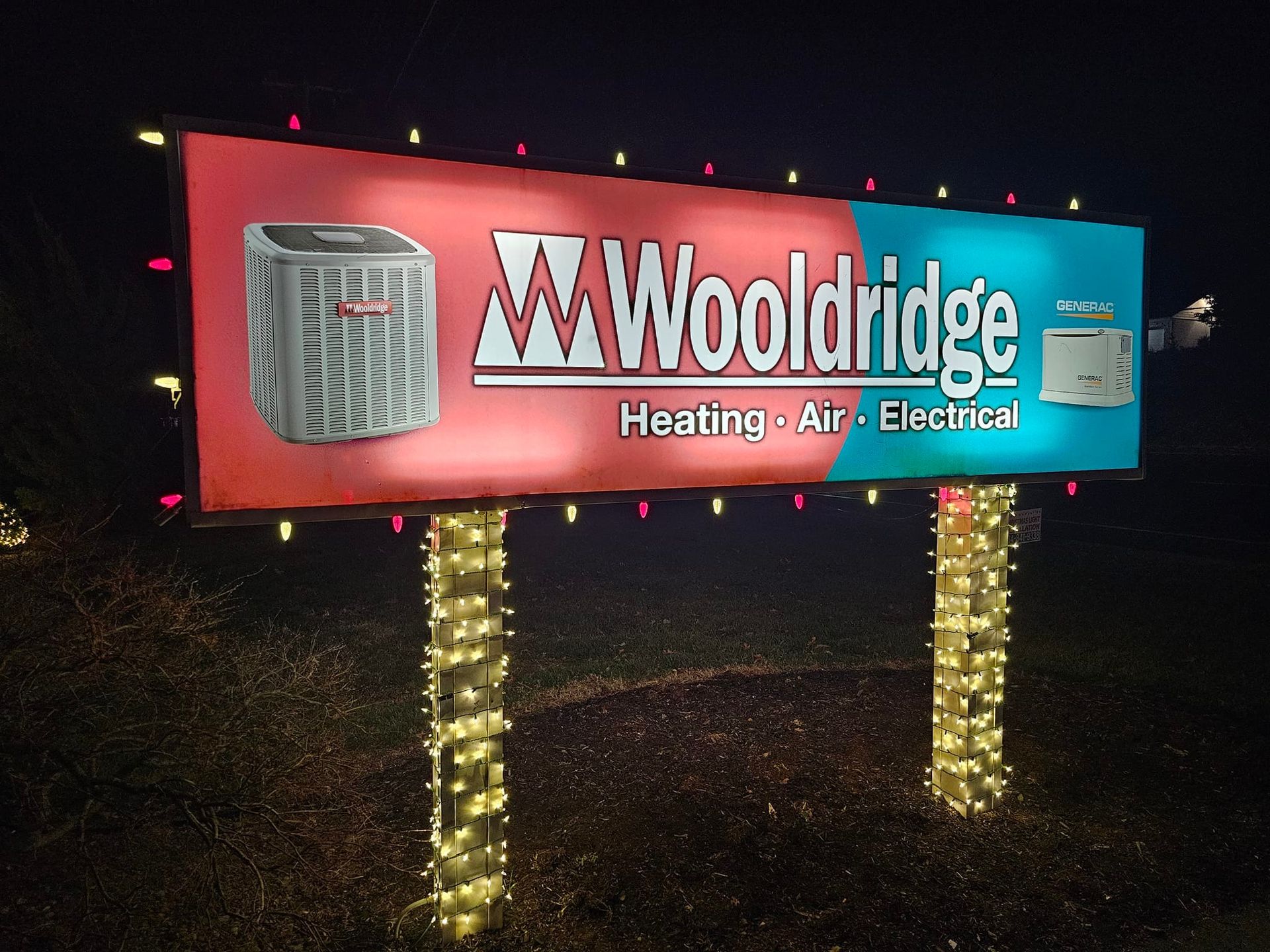 Sign for Woolridge Heating, Air & Electrical, illuminated with lights, against a dark background.