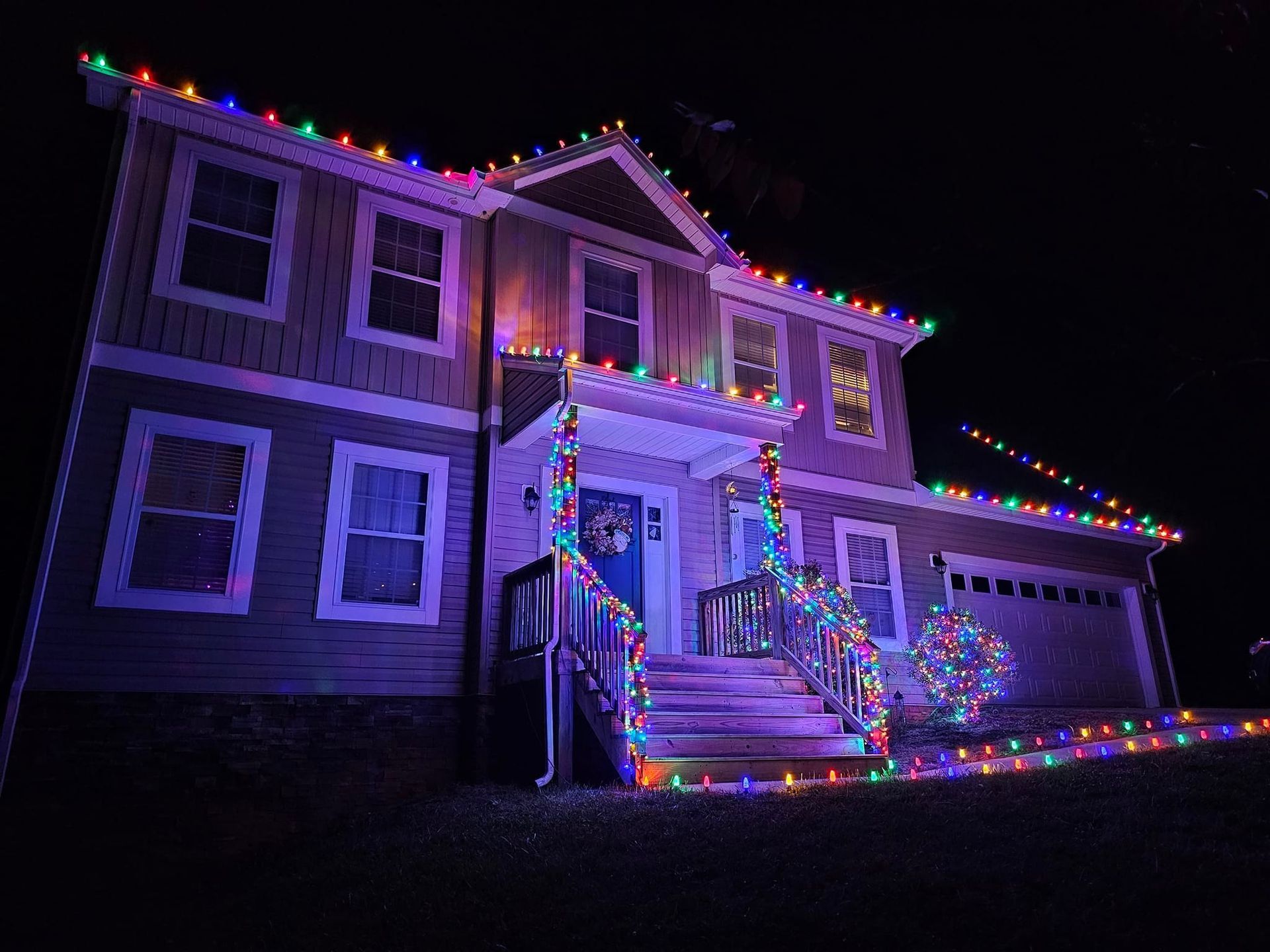 House decorated with colorful Christmas lights at night.